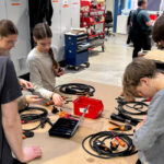 Ein Kurre-Mitarbeiter und vier Kinder an einer Werkbank.