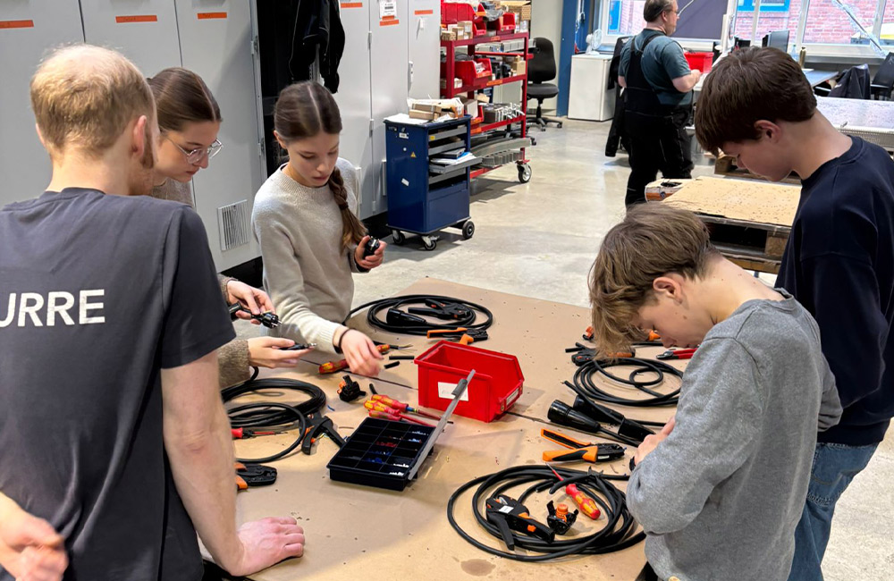 Ein Kurre-Mitarbeiter und vier Kinder an einer Werkbank.