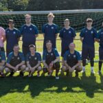 Fußballmannschaft aus Männern vor einem Tor.